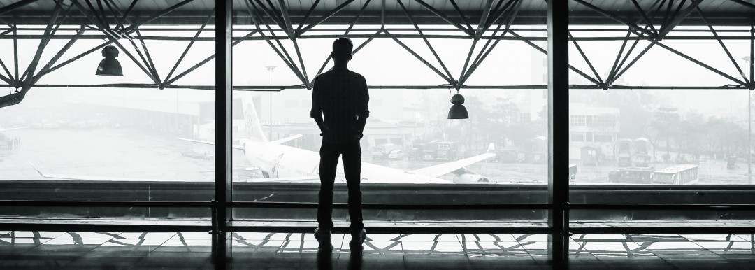 person looking out of window in airport